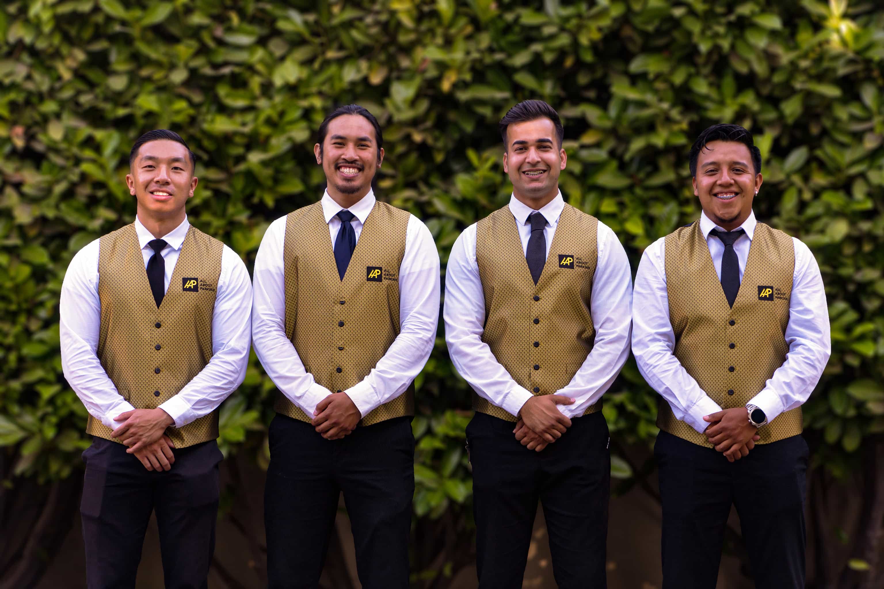 Four valet staff in gold vests smiling for a team photo