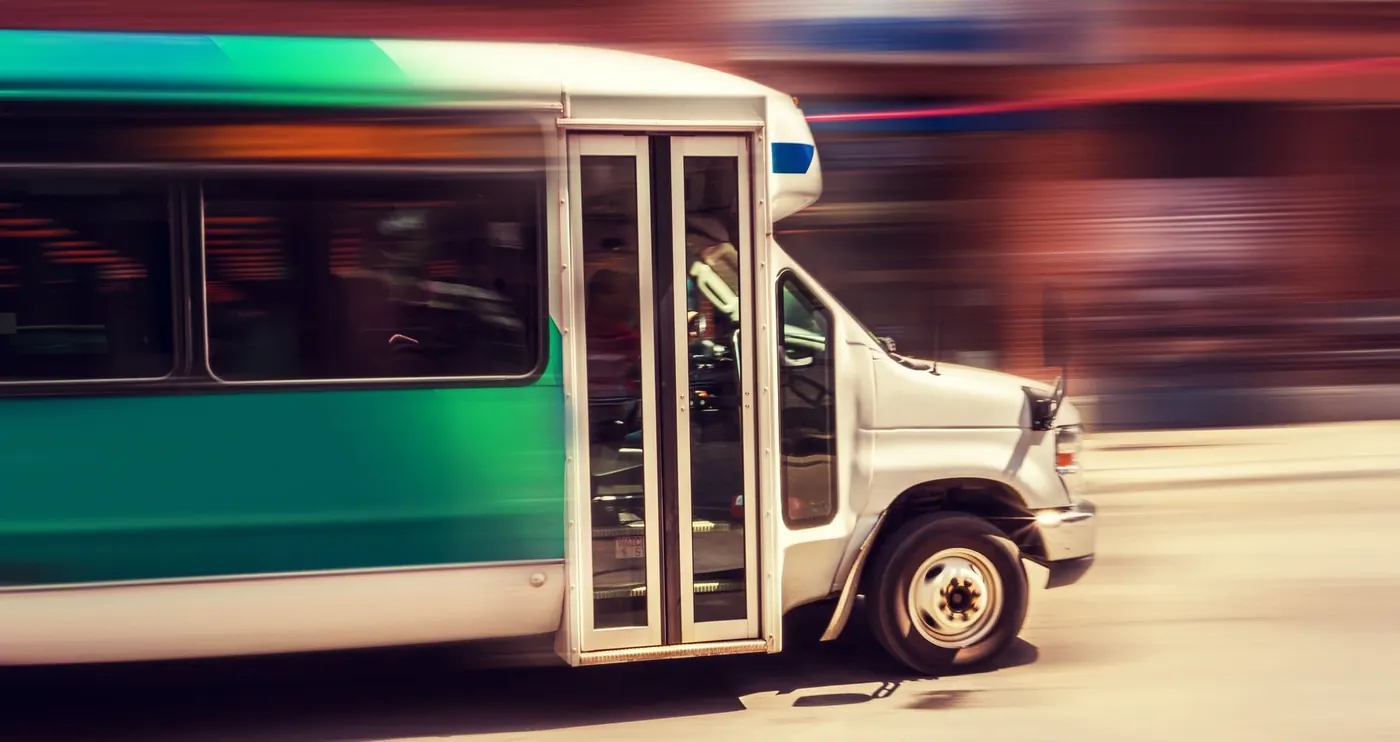 Professional shuttle bus in motion transporting passengers through a Bay Area street